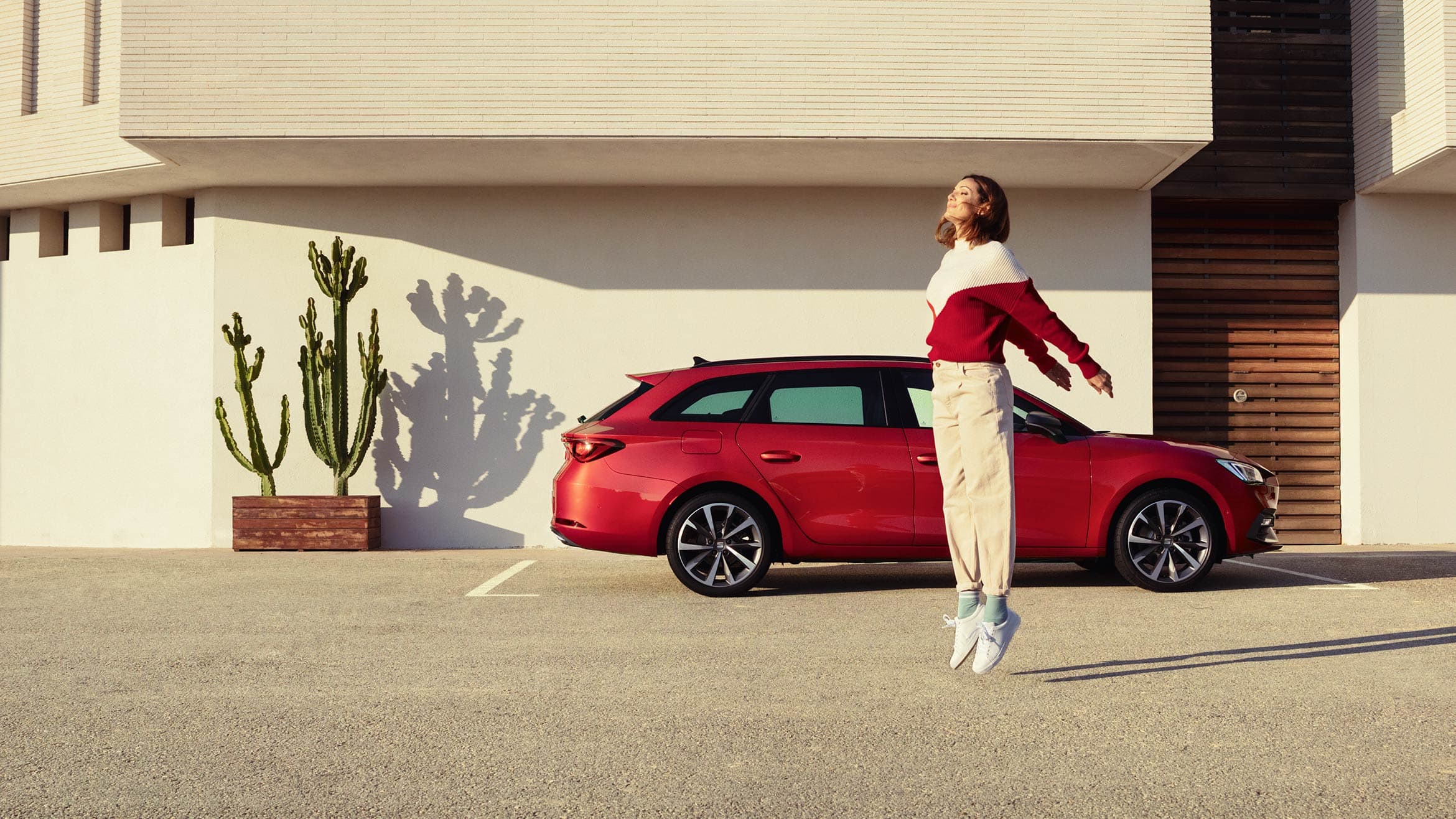  woman jumping next to seat leon sportstourer desire red colour.