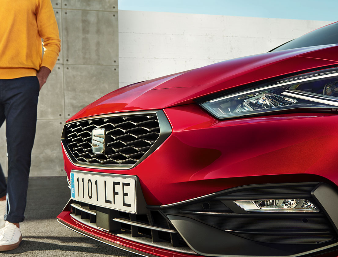 man standing in front of seat leon desire red colour with a bolder front grille