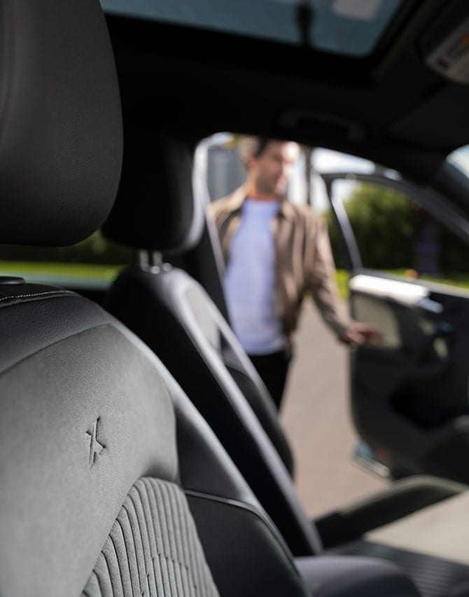 Man in front of a charging new SEAT Tarraco XPERIENCE Dark Camouflage colour with alloy wheel