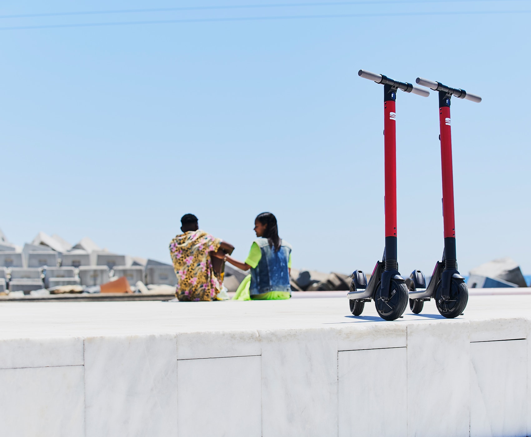 Couple sitting beside SEAT EXS KickScooter urban mobility