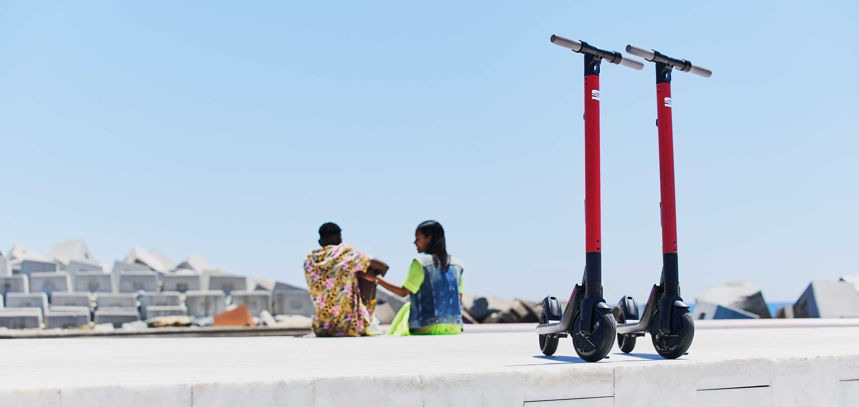 Couple sitting beside SEAT EXS KickScooter urban mobility